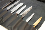 interior of handmade leather knife roll showing seven pockets containing Japanese chef knives.